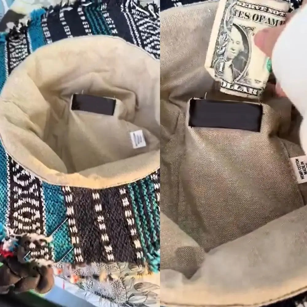 Close-up of a beige bag with a black strap on a patterned fabric background.